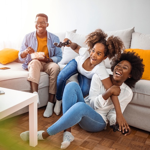 Small family playing video games together while on a couch.
