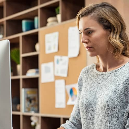 Image of woman on desktop computer reviewing financial statements.