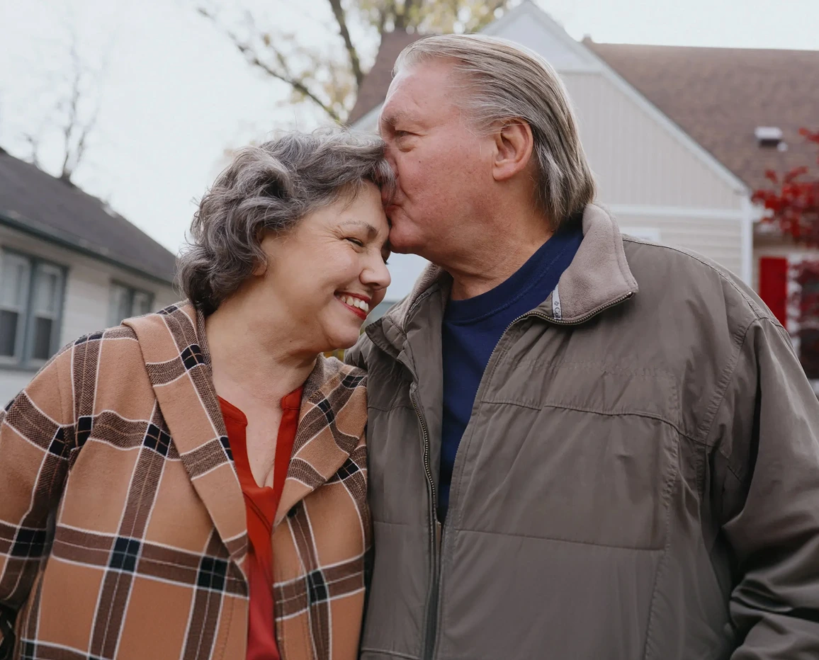 Older couple standing together outside a home.