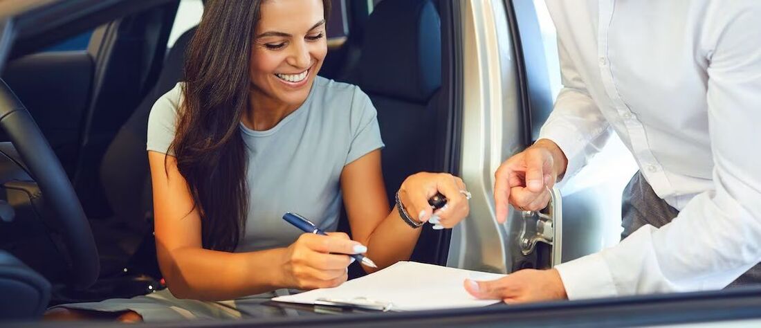 Woman signing paperwork to buy a car.