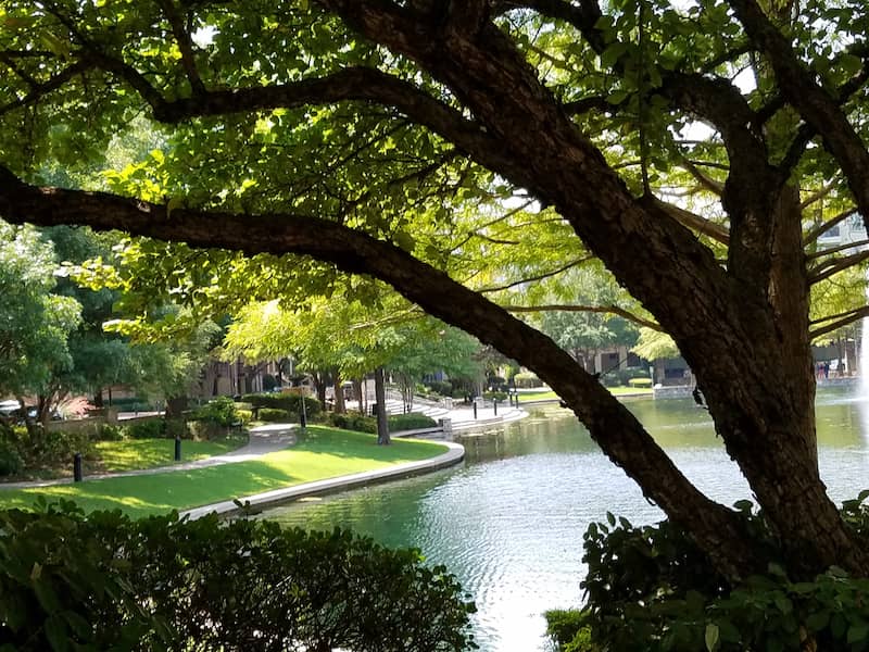 RHB Assets From IGX: Tranquil Riverwalk in Plano, Texas, with a water feature and pedestrian bridge.