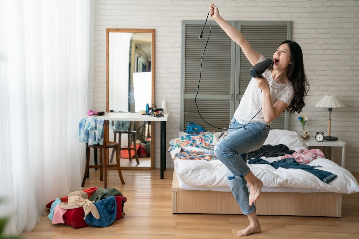 RHB Assets From IGX: Woman singing into a hairdryer like a microphone.