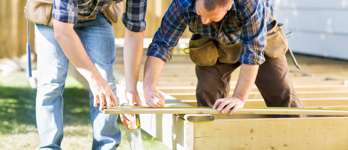 Image of men measuring wood boards for backyard deck.