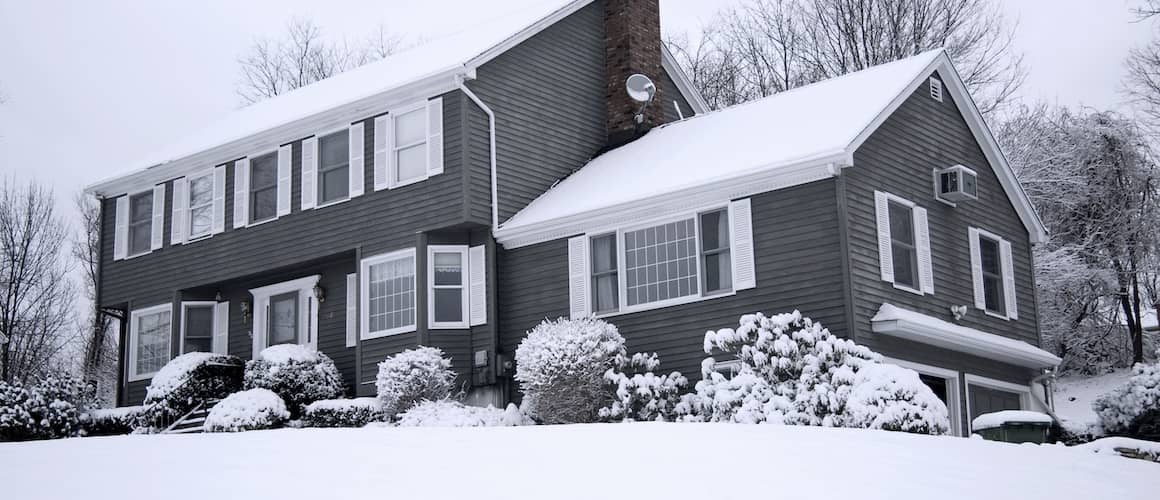 Gray, two story home covered in snow in winter.