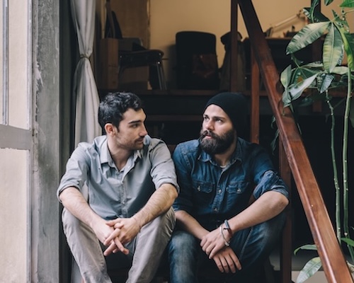 Two young men sitting on stairs and talking.