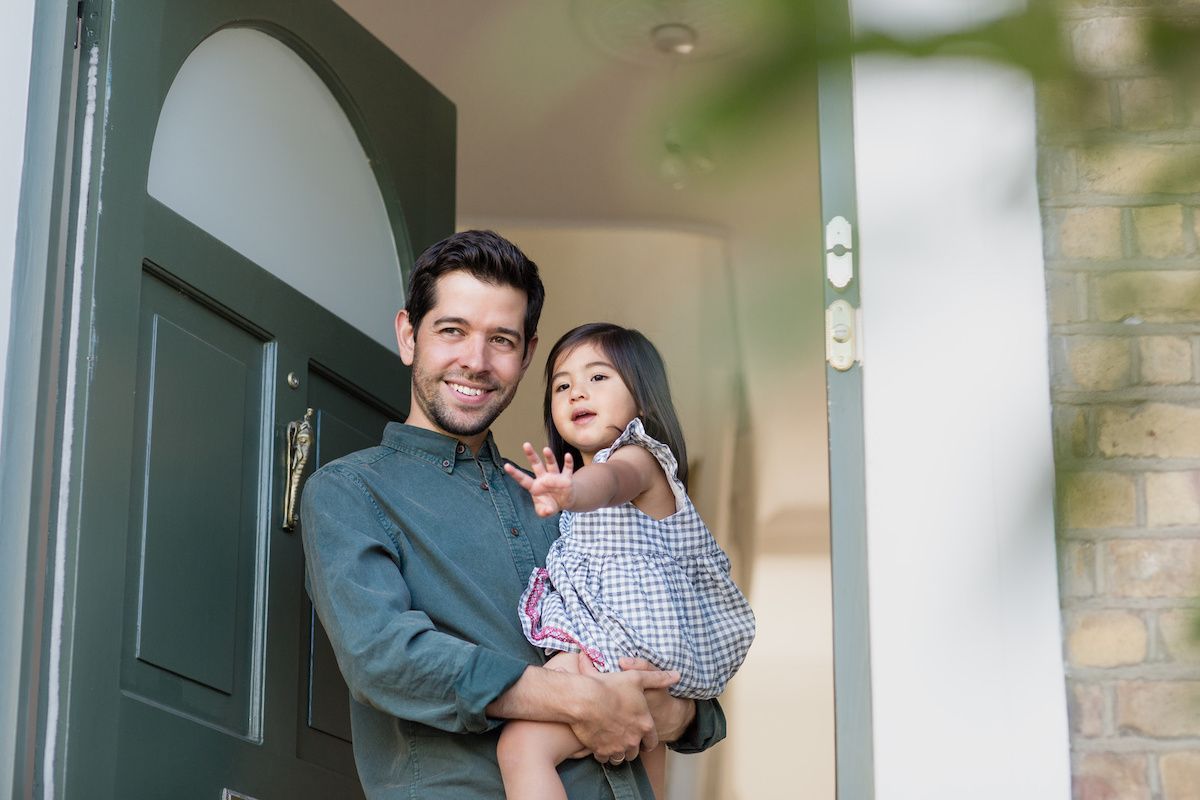 RHB Assets From IGX: A father and his daughter standing in front of a door, smiling.