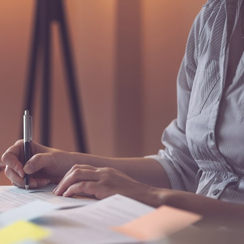 A woman writing something on paper possibly working on taxes or finance.