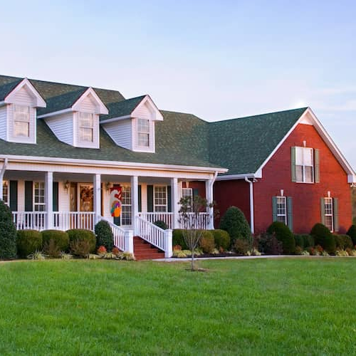 A large brick house in the countryside at dusk.