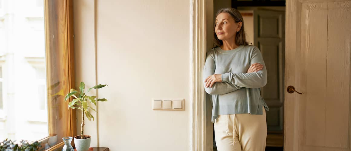 RHB Assets From IGX: An older woman posing in a doorway looking through a window.