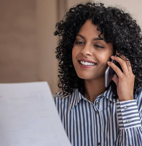 Woman on phone looking over financial documents.