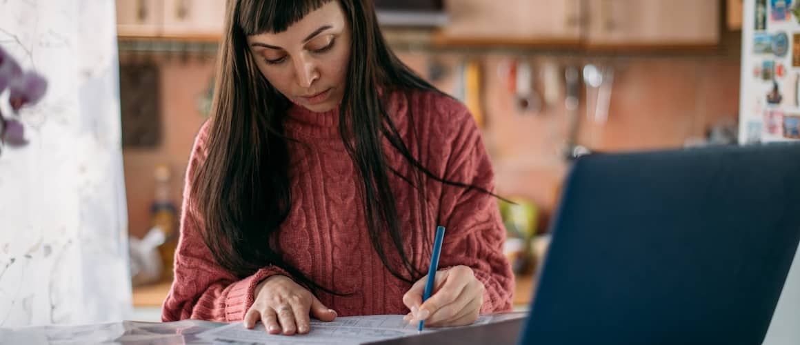 Woman working on her budget at the dining room table. 