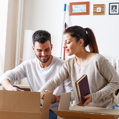 A man and women unboxing cardboard boxes after moving into the new residence.