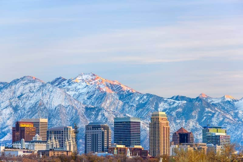 Large snowcapped mountains in Utah behind skyscrapers.