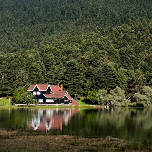 Large home on lake surrounded by pine forested mountains.