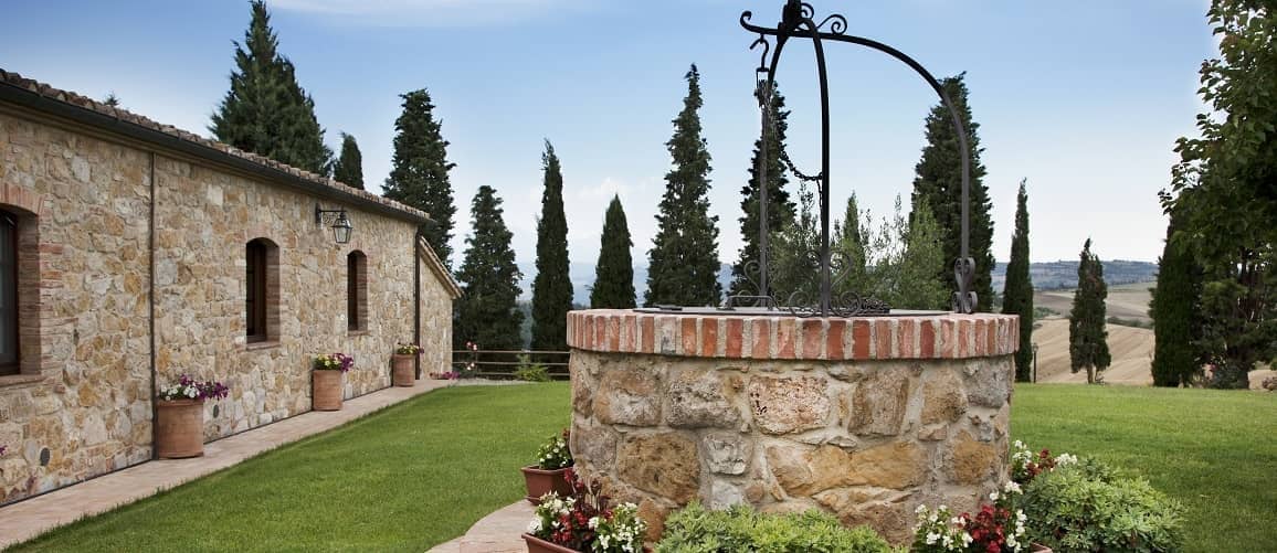 A well in front of a house, adding a rustic and traditional touch to the property's exterior.