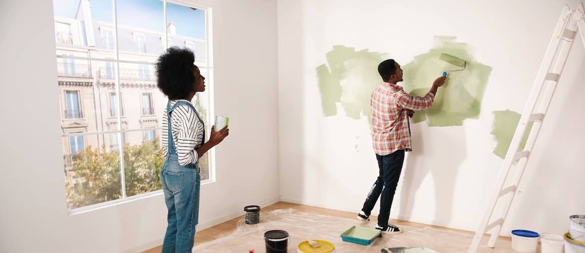 African American couple painting their apartment walls green.