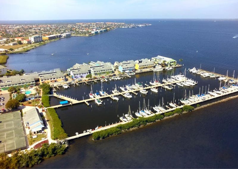 Aerial view of sailboats anchored along piers with  coastal city in the background.