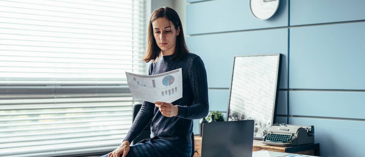 Woman sitting on her desk and reading a financial report.