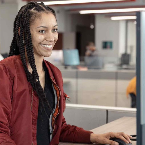 Young woman smiling while working at her desk in office.
