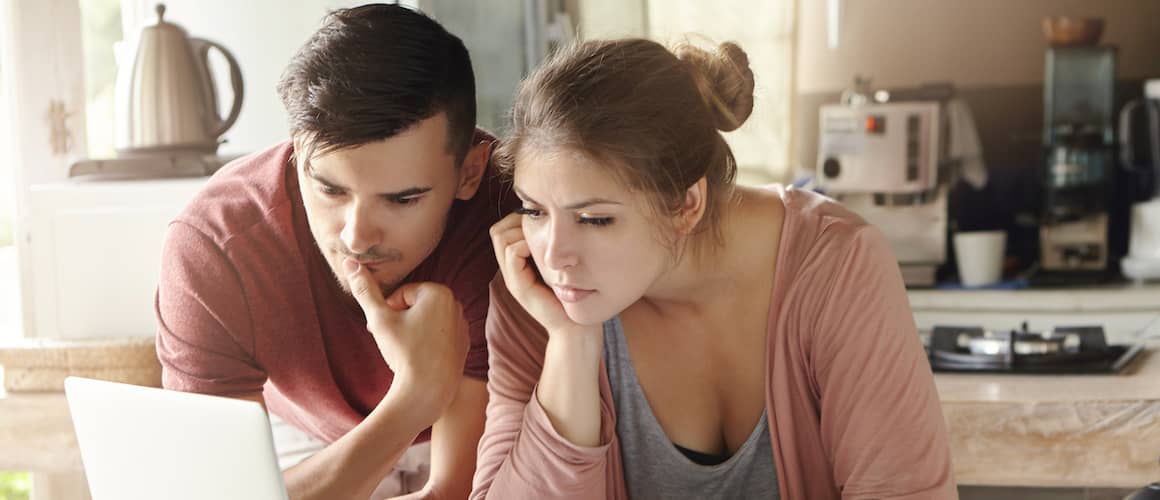 Young couple looking concerned while looking at a computer.