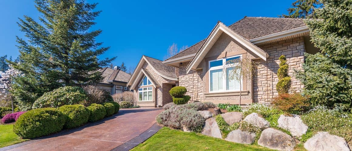 An elegant home featuring a driveway and meticulously designed landscaping.