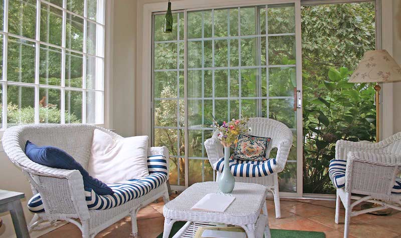 RHB Assets From IGX: Wicker wonderland sunroom with white wicker furniture and greenery.