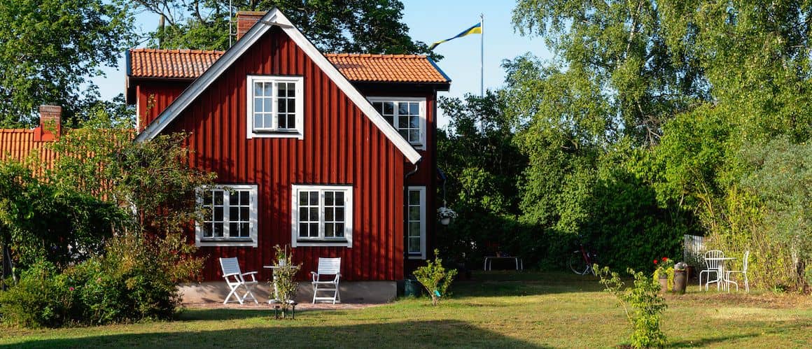 A red house with a small patio, showcasing a residential property with distinct exterior color and design.