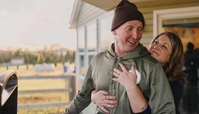 Woman hugging man while he grills.