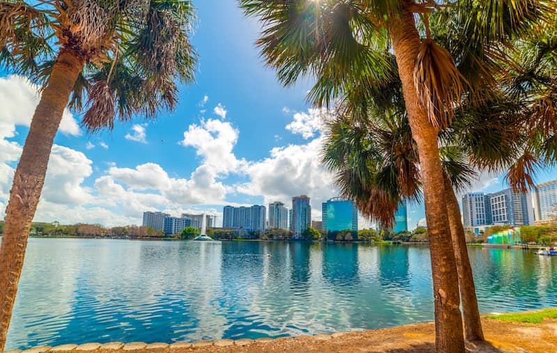 Orlando, Florida coast with palm trees, calm blue water and the cityscape in the background. 