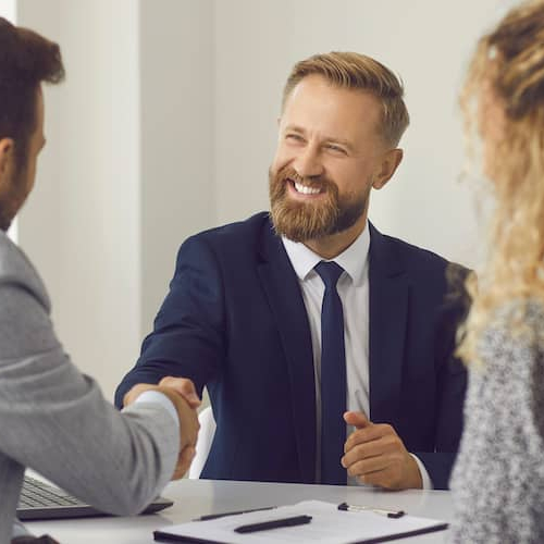 A financial advisor shaking hands with clients, possibly illustrating a successful financial consultation or agreement.