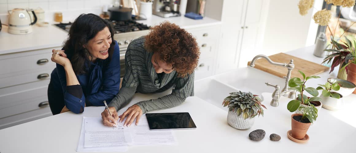 Two women sitting at a table calculating finances.