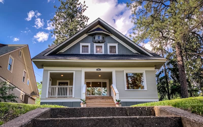 Craftsman bungalow in shades of blue with unique window detail at the peak. 