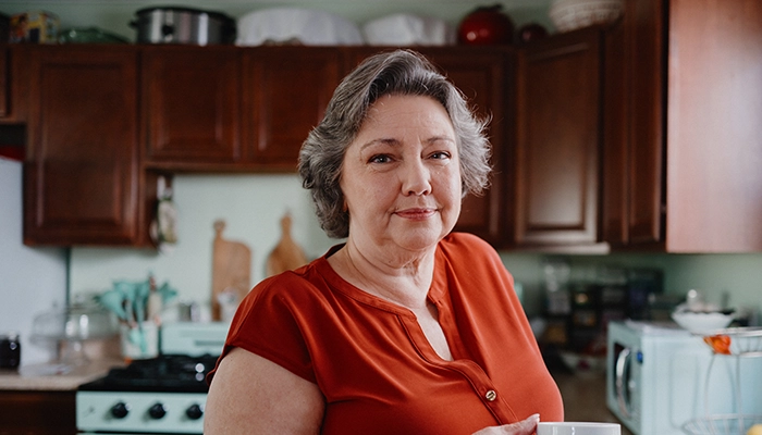 Woman standing kitchen holding coffee cup.
