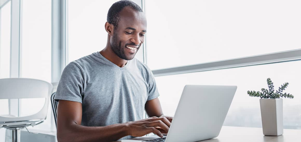 A man working on a laptop in a modern indoor setting.