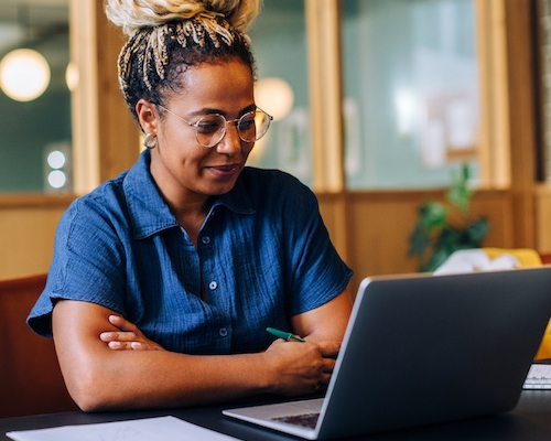 Woman on laptop in office smiling.