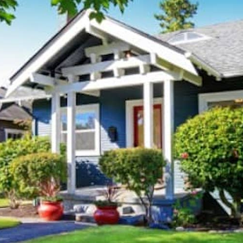 A cozy blue home with bright green grass.