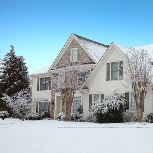 Large white house with brick front in the winter.