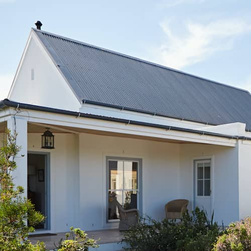 Exterior of white two-story countryside house with black shutters and roof.