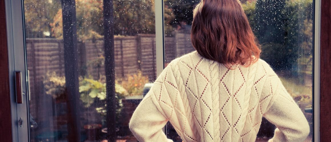 A woman looking out of a window, potentially indicating contemplation or assessing a property's view.