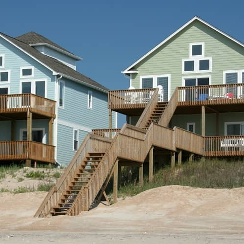 Beachfront home against a blue sky, representing luxurious coastal properties.