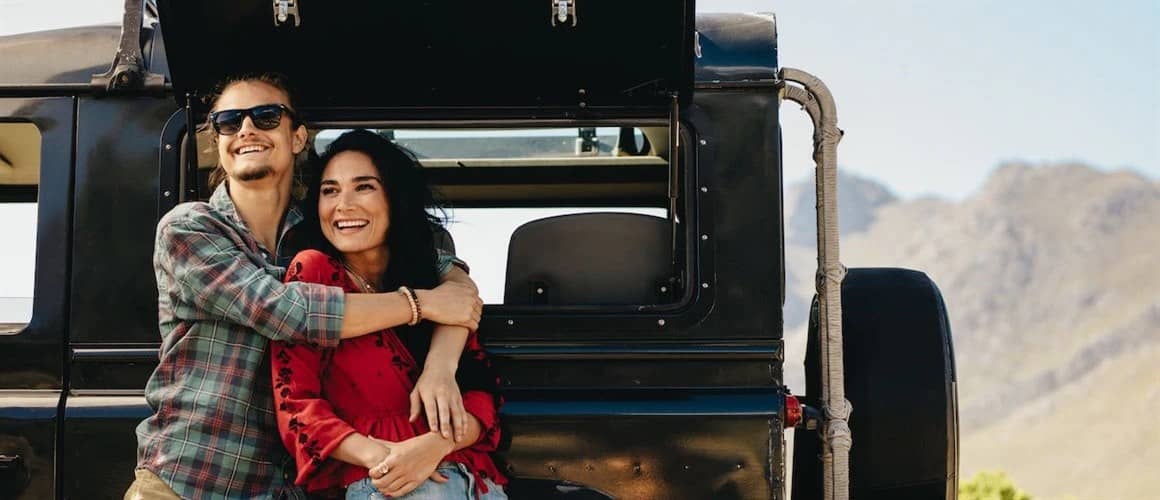 Image of couple posing in front of new car.