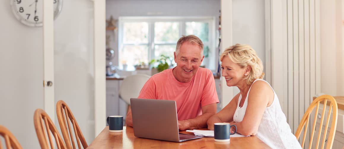 Older couple looking at computer and smiling together.