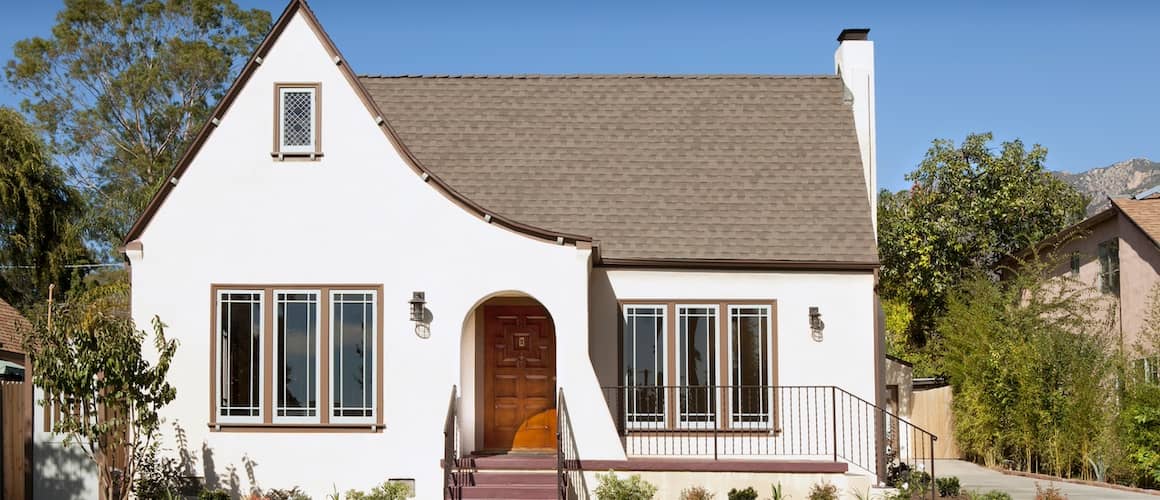 White stucco bungalow with sloped roof and red door.