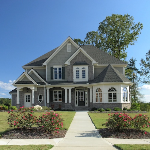 Large grey luxury suburban house with sidewalk.