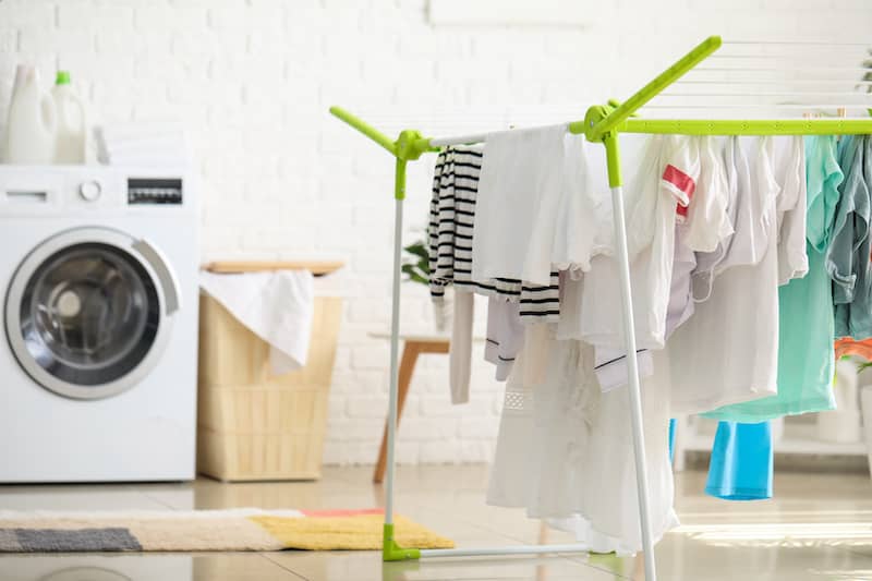 RHB Assets From IGX: Clean and organized laundry room with clothes hanging on a dryer rack.