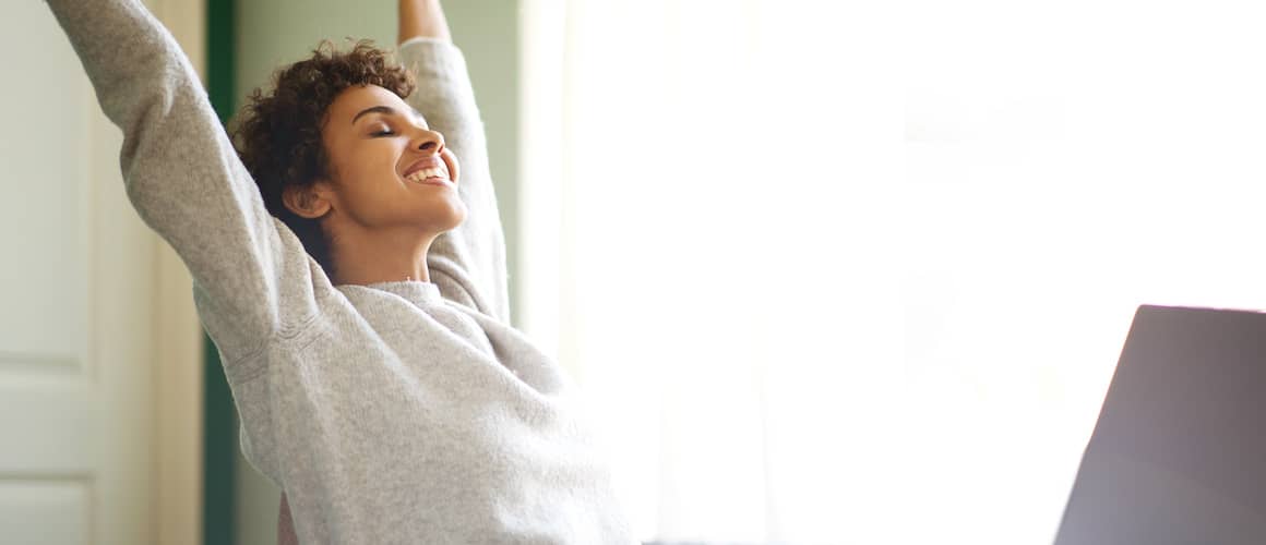 Woman with arms in air after getting approved for a personal loan online looking happy.