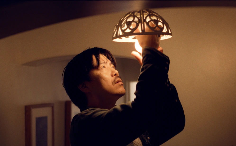 An Asian man changes a lightbulb in his new home.