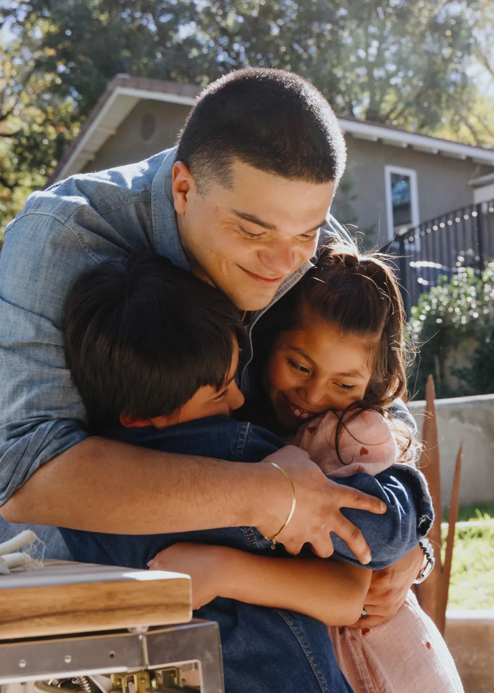 A young man embraces his family members outside of his new home.