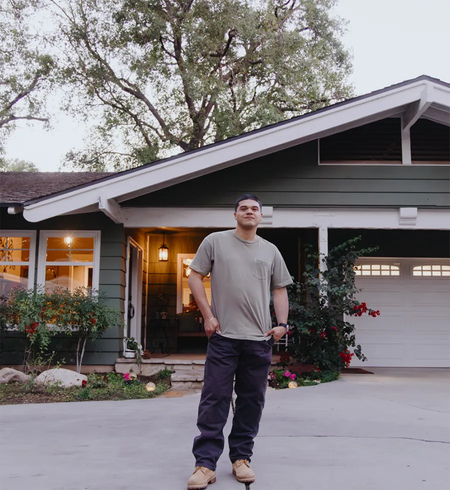 A man proudly poses in front of his new home.