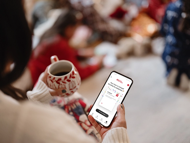 A person holds a coffee cup and a smartphone that shows a loan-closing screen.